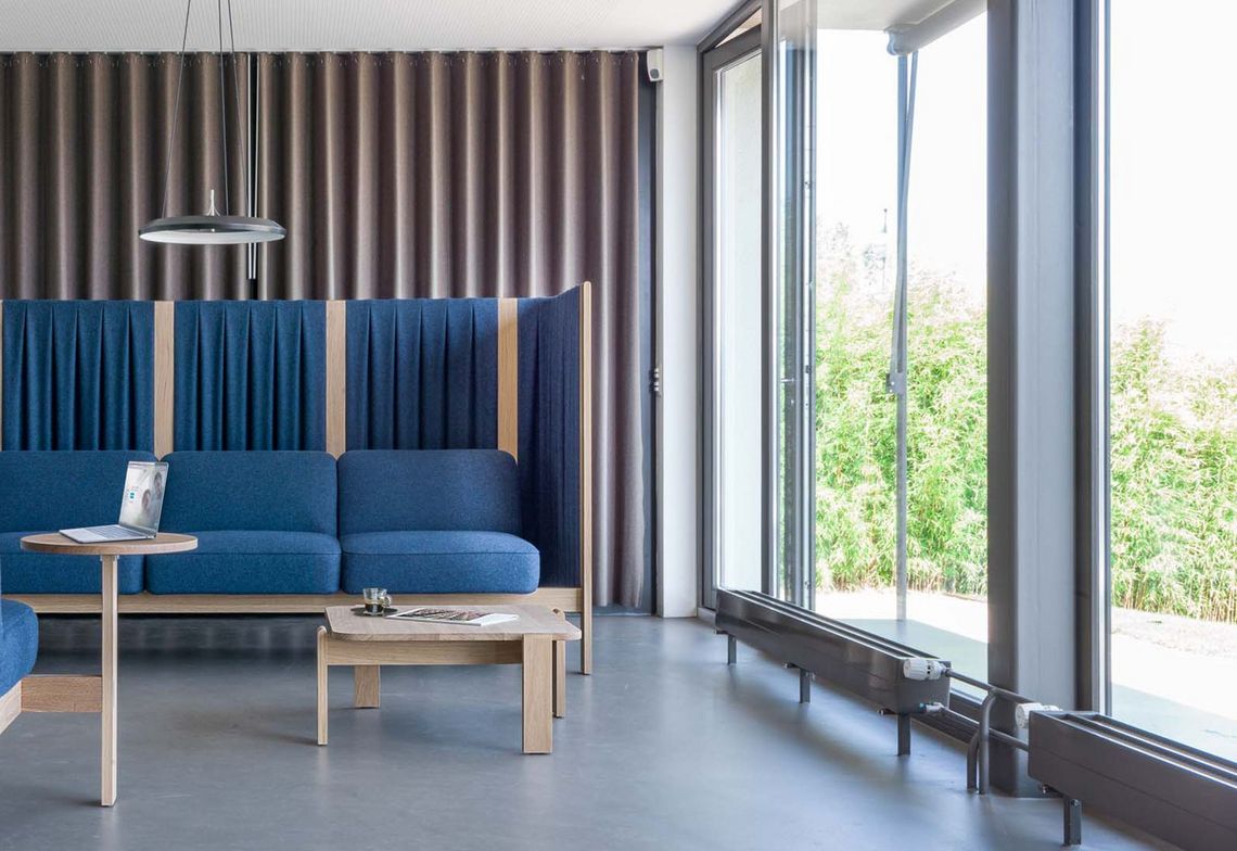 Dreisitzer Loungesofa und Sessel blau gepolstert mit Seitenpaneelen im Wartebereich